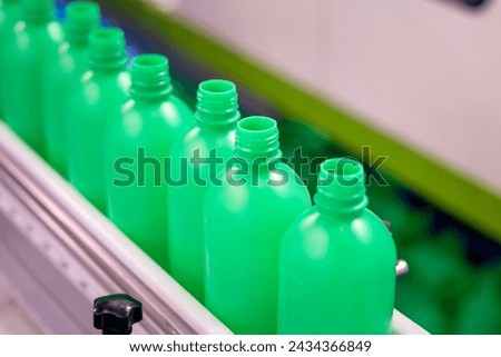 Stream of Green Plastic Bottles on Industrial Production Line. Automated Bottle Manufacturing in Progress. The Conveyor Belt of Green Bottles in a Modern Factory Setting