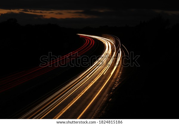 Stream\
of light trails on motorway at night into\
sunset