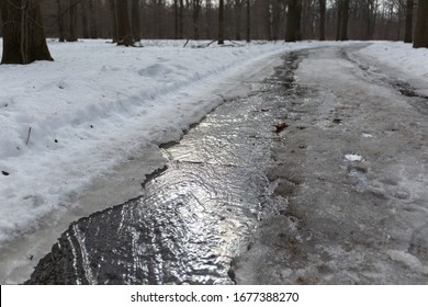 A Stream Of Melted Snow On The Asphalt. Road With Melted Snow And Ice In Early Spring. Spring Puddles, Snow Drifts, Snow, Mud And Melted Dirty Water Stream