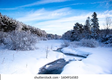 Stream running through a snow covered Wisconsin forest with snow covering the trees in January, horizontal - Powered by Shutterstock
