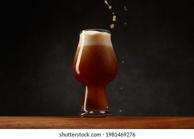 Stream Of Stout Beer Pours Into A Beer Glass On A Bar Counter. Glass Of Beer On Dark  Background. Dark Ale Beer With Foam Head. Selective Focus