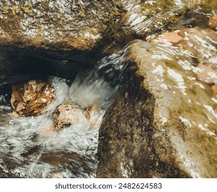 A stream of water flows down a rocky hillside. The water is clear and calm, and the rocks are grey and rough

 - Powered by Shutterstock