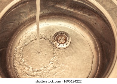 A Stream Of Water Pours Into The Iron Sink.