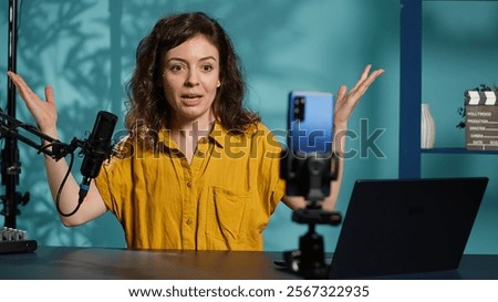 Streamer doing live broadcast on smartphone on holder, talking to audience about recent news headlines. Media star talking with viewers, presenting facts in entertaining manner, camera A