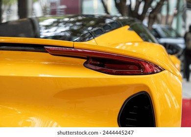 Streamlined rear bumper with elegant stop lights of expensive yellow car. Exterior surface covered with glossy plastic creating downforce while driving allowing to reach high speeds