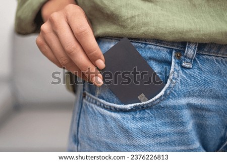 Streamlined shopping: A lady's hand pulls a dark credit card with a chip from her jeans pocket, simplifying online payments for ordered goods, the epitome of convenient shopping. 