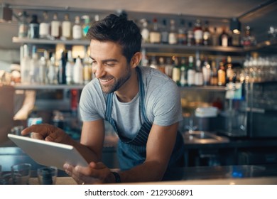 Streamlining small business tasks with smart tech. Shot of a young man using a digital tablet while working behind a bar counter. - Powered by Shutterstock