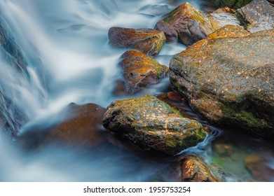 Streams of water over stones and autumn leaves Ularsky waterfall