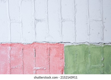Street art detail. Green, pink, grey and white brick wall texture background. Geometric pattern on house wall. Creative, stylish backdrop. Painted stone structure. Close up, copy space
