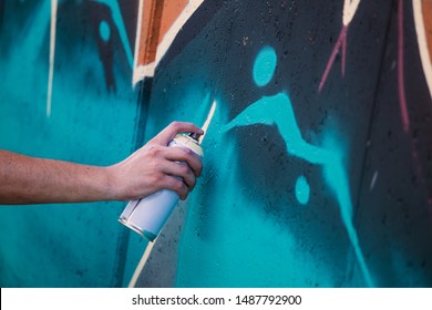 Street artist painting colorful graffiti on generic wall - Modern art concept with urban guy performing and preparing live murales with multi color aerosol spray - Shutterstock ID 1487792900
