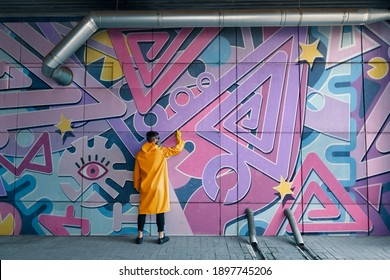 Street artist painting colorful graffiti on wall Modern art, urban concept.