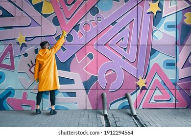 Street artist painting colorful graffiti on wall. Modern urban art concept
