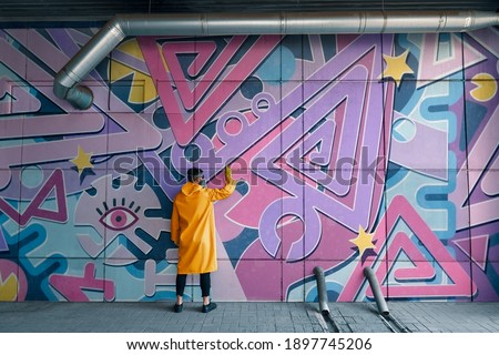 Street artist painting colorful graffiti on wall Modern art, urban concept.
