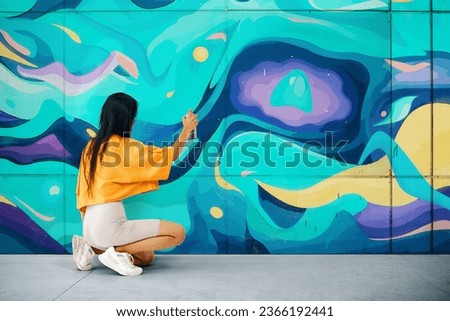 Street artist painting colorful graffiti on wall Modern art, urban concept.