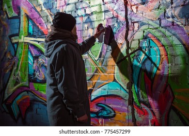 Street Artist Painting Graffiti With Aerosol Paint On Wall At Night