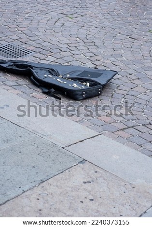 A street artist's guitar case with coins on a city street of Padua, Italy