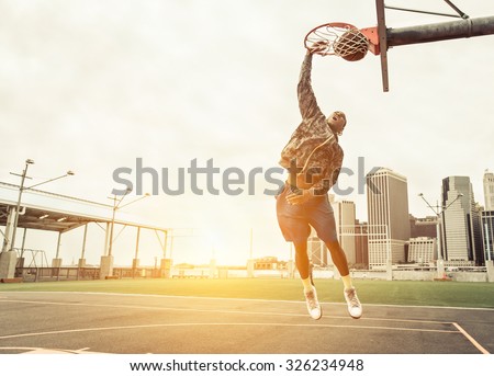 Street basketball player performing power slum dunk. Manhattan and New york city in the background