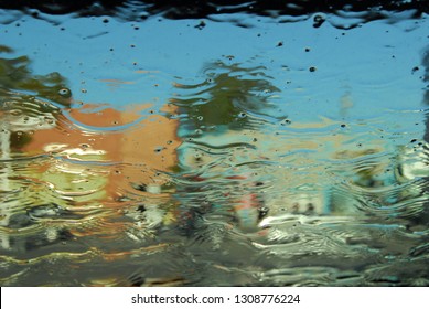 A Street And Buildings Seen Through Sheets Of Water Running Down Glass