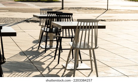 Street Cafe Chairs And Tables In Sun Rays. No People. Empty Outdoor Table In Street Cafe. Traffic