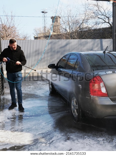 \
Street car wash\
self-service.\
Washing in the open air.\
A man washes a vehicle\
with shampoo under strong water pressure. Property maintenance, dry\
cleaning