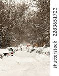 The street and cars are full of snow after a big snowstorm during winter season in Montreal, Quebec.  People shoveling.  More than 30 cm in 1 day on the city.