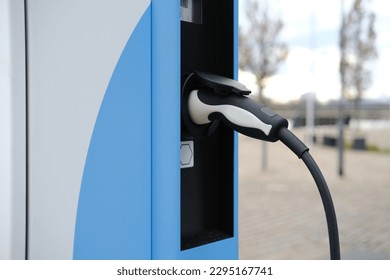 street, charging with electricity through cable, electric vehicle in European city, eMobility charging, energy accumulators, alternative energy development, technology and innovation