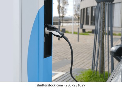 street, charging with electricity through cable, electric vehicle in European city, eMobility charging,energy accumulators, alternative energy development, technology and innovation