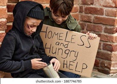 street child boy looks at bank with donation money, want to buy some food, sitting on street
