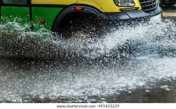 Street of the city flooded after heavy rains. Large\
puddles in the streets after the rain. Bright background splashes\
from under the wheels of the cars driving on the puddles. Strong\
motion blur