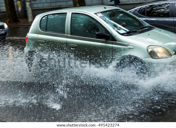 Street of the city flooded after heavy rains. Large
puddles in the streets after the rain. Bright background splashes
from under the wheels of the cars driving on the puddles. Strong
motion blur