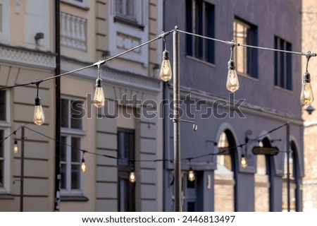 a street in a city with installations for small lamps between poles