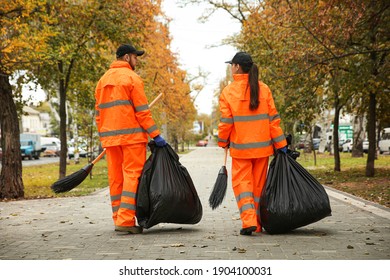 Street cleaner with brooms and garbage bags outdoors on autumn day, back view