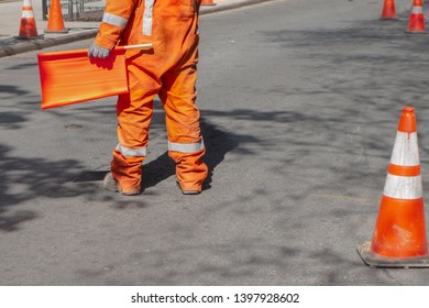 Street Construction Zone With Orange Suited Man Directing Traffic With Orange Flag