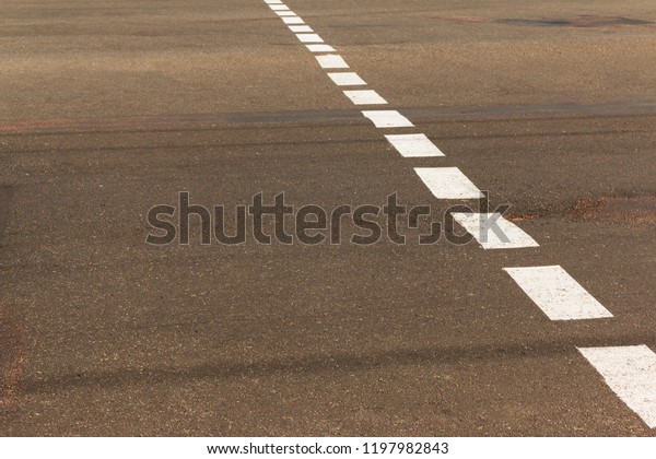 Street crossing\
with white dotted line. Asphalt road crosswalk with marking lines\
white and yellow\
stripes\
