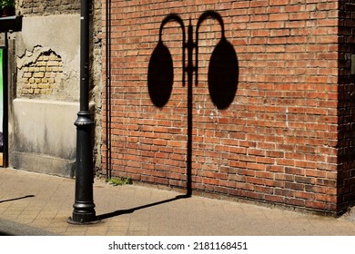 street detail with sidewalk, brick wall and street lamp shadow. shadow play concept. old european streetscape. bright summer lights. spalling stucco finish. travel and tourism concept. running bond.
