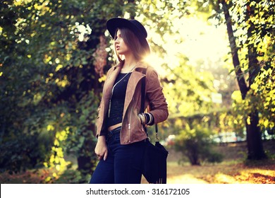 Street Fashion Concept - Closeup Portrait Of A Pretty Girl. Wearing Hat And Suede Jacket  Holding Bag With Fringe. Beautiful Autumn Woman. Artsy Bohemian Style. Outside, Fall Fashion