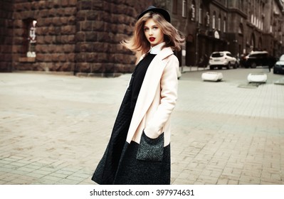 Street fashion concept. Vintage portrait of young woman in spring coat and hat. Flattering hair.