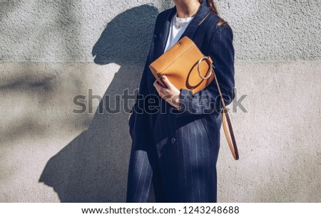 street fashion detail of  woman wearing a navy blue pinstriped coat holding a  leather purse