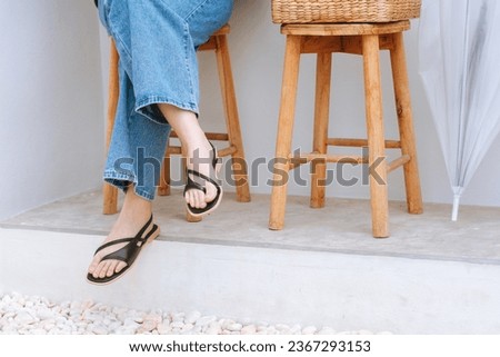 Street fashion details of elegant woman`s summer outfit: blue jeans, black strap sandals. Street style, summer fashion trend, footwear, sandals, fashionable accessories, perfect skin, noface.