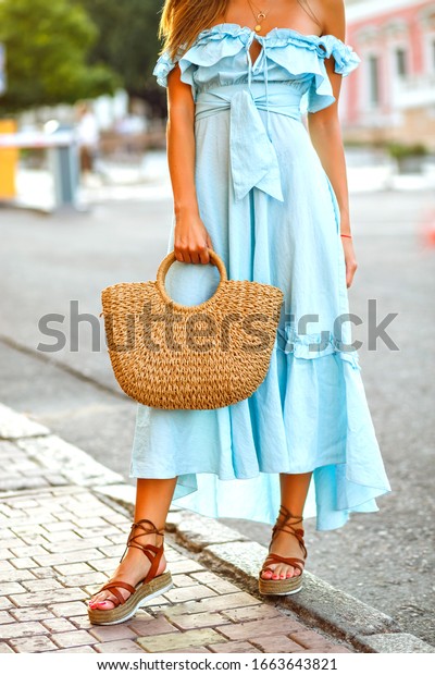 Street fashion details of\
stylish elegant woman wearing trendy blue vintage ruffle dress,\
gladiator sandals and straw bag, summer vacation relaxing\
style.
