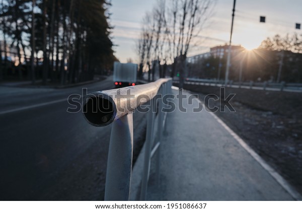 Street fence at sunrise, city stream of cars\
stands in traffic.