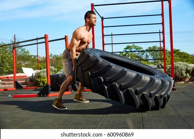 Street Fitness Workout Muscular Man Lifting And Rolling A Huge Tyre At Outdoor Gym.