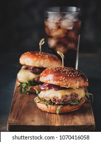 Street food, fast food. Homemade juicy burgers with beef, cheese and caramelized onions on the wooden table. Toned image.