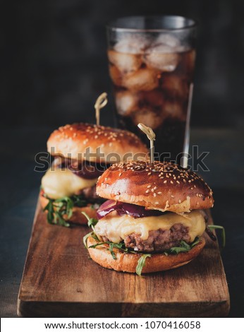 Street food, fast food. Homemade juicy burgers with beef, cheese and caramelized onions on the wooden table. Toned image.