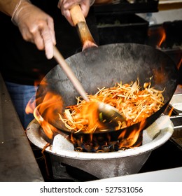 street food. fried noodles in a wok with chicken and shrimp on the open fire