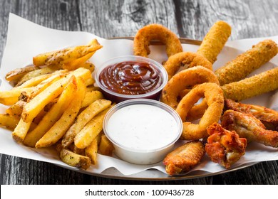 Street food plate with mozzarella sticks, chicken wings, onion rings, french fries and dip. - Powered by Shutterstock