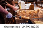 Street food of Prague. Traditional national Czech sweet food. Tubes of sweet dough, cooked on an open fire. Popular dessert in Prague. Grilled food. Manufacturer trdelnik. Selective focus.