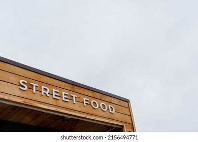 Street food sign hanging against the sky, catering establishment in the city, fast food on the street, concept text fast food, letters on a wooden background. High quality photo - Shutterstock ID 2156494771