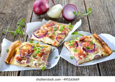 Street Food: Slices Of Hot Baked Tarte Flambee From Alsace With Onions, Bacon And Sour Cream Served On Parchment Paper