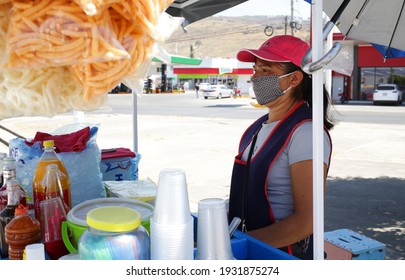 street food snacks vendor woman on a sunny day wearing face mask, Jalisco, Mexico - March, 2021